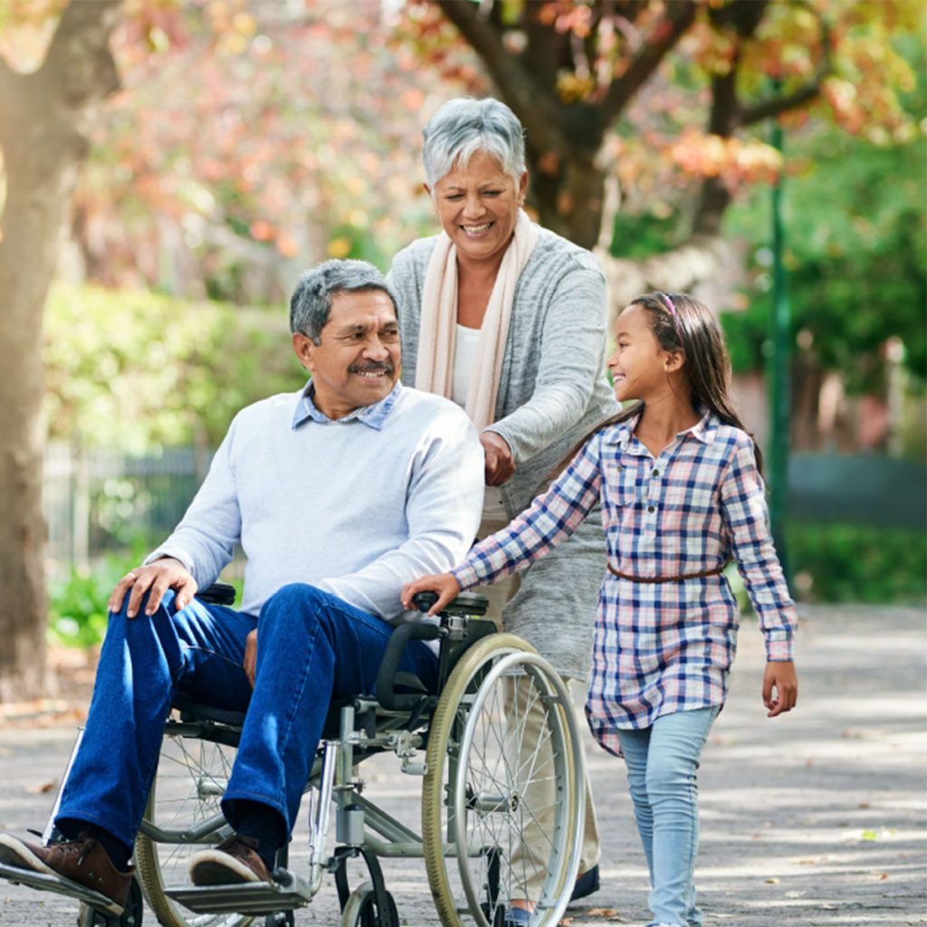 Child and caregiver smiling with man in wheelchair